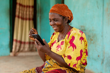 elderly african woman holding her smartphone rejoices