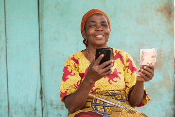 elderly african woman holding phone and money