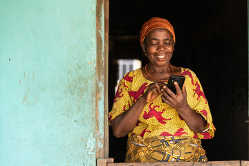 happy elderly african woman using her phone - obrazy, fototapety, plakaty