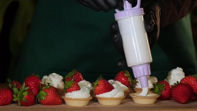 Chef sprinkling sugar powder on tasty mini cake with cream and strawberries, slow motion. Powdered sugar being sieved on strawberry tart. Dessert dusted with castor sugar
