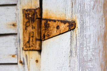 Old Rusty hinge on peeling white painted wood