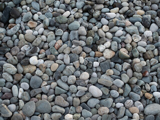 Smooth round pebbles texture background. Pebble sea beach close-up, dark wet pebble and gray dry...