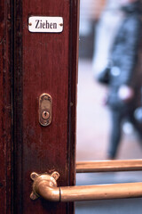 Close-up of the German word ziehen, or pull, written on an old vintage wooden door with gold metal lock and doorknob.