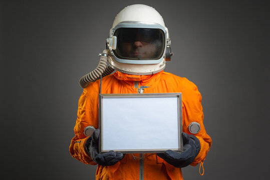 Astronaut holding in hand a blank diploma certificate with copy space. Space message. Space program goals tempalte.