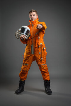Serious astronaut is standing in the space suit and helmet on the gray background.