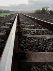 Close up of railway track with cloudy sky, dark background, selective blurred focus