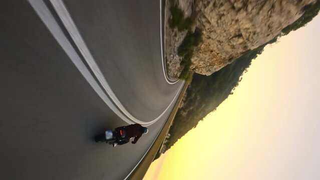 Two Motorcyclists driving on a serpentine road during golden sunrise, vertical