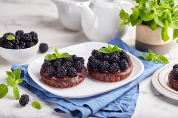 Chocolate mini cakes with chocolate cream and blackberries. Delicious homemade dessert.