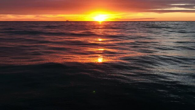 Aerial panoramic footage of ocean waves with cruiser on background. Slow motion. Beautiful sunset landscape with horizon.