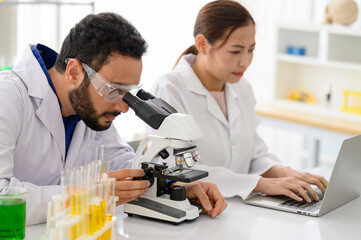 Chief research scientist adjusts specimen in petri dish and looks into microscope