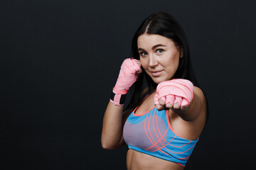 Sportsman woman boxer with jab punch at black background