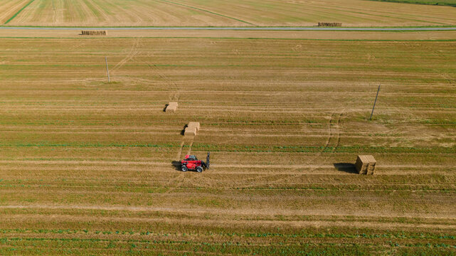 Agricultural tractor collect wheat straw into briket for transportation. Aerial view. Agricultural machinery