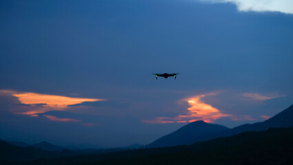 Fototapeta na wymiar Silhouette of a drone during the sunset or sunrise, unmanned aerial vehicle in the outdoor