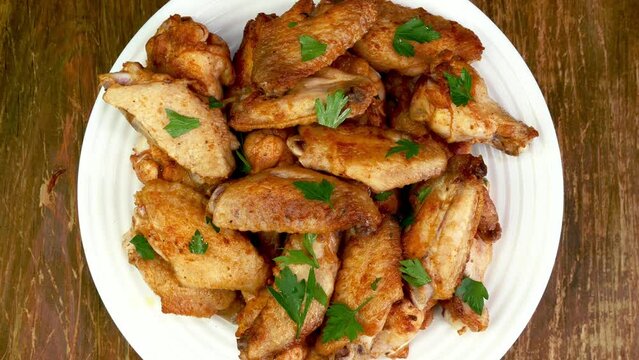 Many fried, sprinkled with parsley, chicken wings.