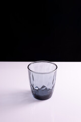 black glass beaker on a black white background. Minimalist