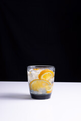 lemonade in a glass with a straw on a white table and black background. Minimalist