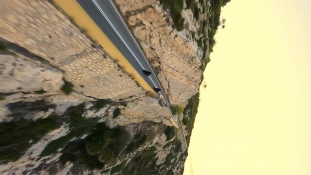 Two Motorcyclists driving on a serpentine road during golden sunrise, vertical