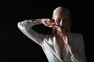 Young blonde albino woman doing face building facial gymnastics self massage and rejuvenating exercises on black background.