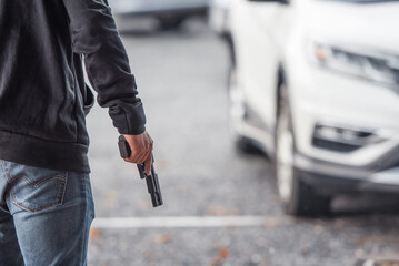 Man with a gun in car park. - 525868916