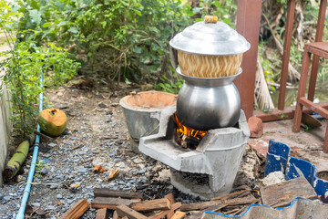 Steaming Sticky rice in wicker bamboo steamer and lid with Laos aluminum steel pot on the charcoal...