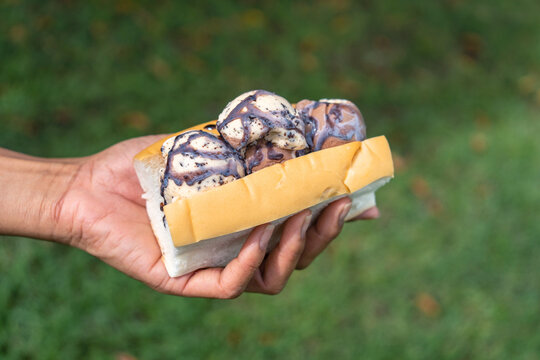 Street food snacks of Thailand. chocolate chip ice cream in bread. Ice Cream Sandwich in hand and green grass background.
