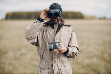 Man controlling fpv quadcopter drone for aerial photography and videography with goggles antenna remote controller.