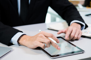 business person holding digital tablet and working with computer, occupation of internet communication technology working in modern indoors office, using hand to touch screen close-up