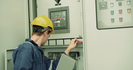 Professional inspector electrician technician engineer in safety uniform helmet hat holding laptop checking power voltage electrical system control panel at industrial factory construction site