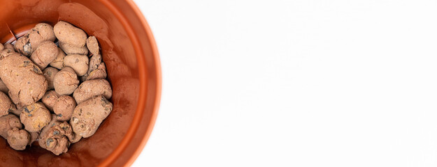 Claydite drainage stones in a pot for houseplants on a white background.