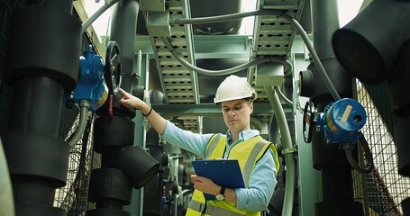 Portrait Professional Inspector Engineer foreman in hardhat working checking the valve pipelines and recheck system data spec on rooftop of construction site	