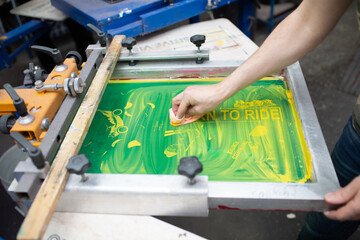 Serigraphy silk screen print process at clothes factory. Cleansing Frame, squeegee and plastisol...