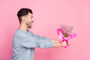 Profile portrait of excited positive person arms hold give flowers bouquet look empty space isolated on pink color background