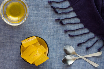 Top view of Indian sweet commonly known as Kesar Angoori Petha or Petha. Bowls placed on blue...