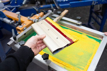 Squeegee for Serigraphy silk screen print process at clothes factory. Frame, squeegee and plastisol color paints.