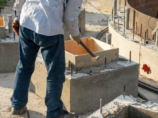A worker removes wooden formwork after the concrete structure hardens at a construction site.