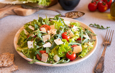 Fresh vegetable salad with tomatoes, arugola, parmesan cheese and other ingredients, healthy eating