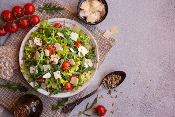 Fresh vegetable salad with tomatoes, arugola, parmesan cheese and other ingredients, healthy eating