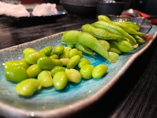 Japanese vegetable dish green beans as an appetizer and dessert served on an oblong turquoise plate