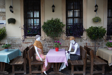 TWo woman mannequin sits at table cafe.
