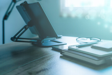 Stylish workplace with telephone and tablet PC on table in home office, beautiful blue fillter