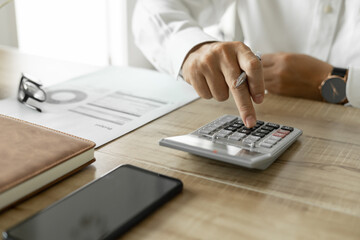 Business man calculating business investment, man in white shirt working on desk in office.