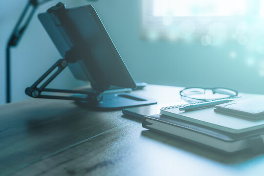 Stylish workplace with telephone and tablet PC on table in home office, beautiful blue fillter