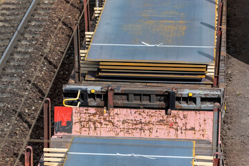 Heap pile heavy raw rusted steel iron sheet plates loaded on railroad cargo freight carriage. Metal goods factory plant products shipping and logistics. Metallurgy industrial transportation service