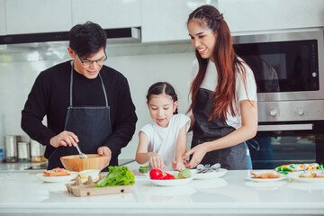 Asian family cooking at home. Happy family cooks together in the kitchen home recreation and weekend meal prep.