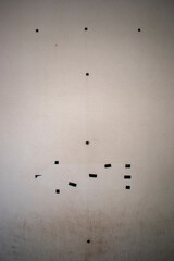 Pieces of black rubber, squares, dots, lines on a beige old and scratched door or wall. Abstract background, desktop wallpaper.