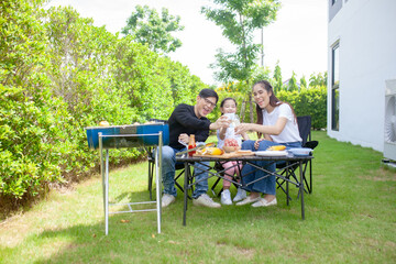 Asian Family Enjoying Camping Holiday In the backyard at home,  Happy family having barbecue with grill outdoors