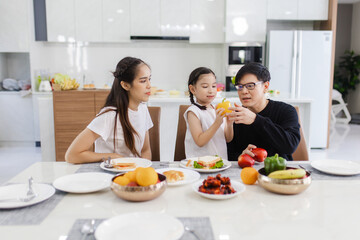 Asian family having meals together and showing thumbs up at home happily, Happy young parents are having fun with their little daughter during lunch at the dining table.