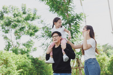 Portrait of a happy Asian family consisting of parents and children happy together for the holidays. Asian Family with a child playing on a lawn,  enjoyment relaxing recreational concept.