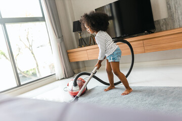young child vacuuming the floor in the bedroom and helping her mom with chores and clean the house, Little girl using vacuum cleaner while helping mother at home