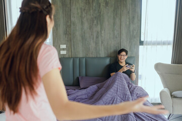 Young woman cannotangry because of her husband playing game on mobile phone in bedroom. boyfriend in bed with phones. People playing on smartphones.